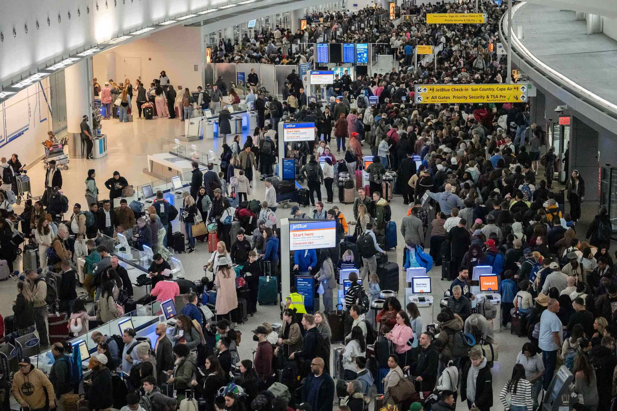 Saguão de aeroporto lotado de passageiros em filas de check-in durante período de pico